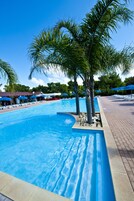 Una piscina al aire libre de temporada, sombrillas