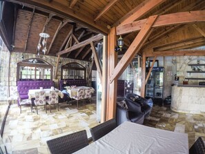 Decoração rústica com parede de pedra, vigas de madeira, um banco roxo e um espaço de bar.