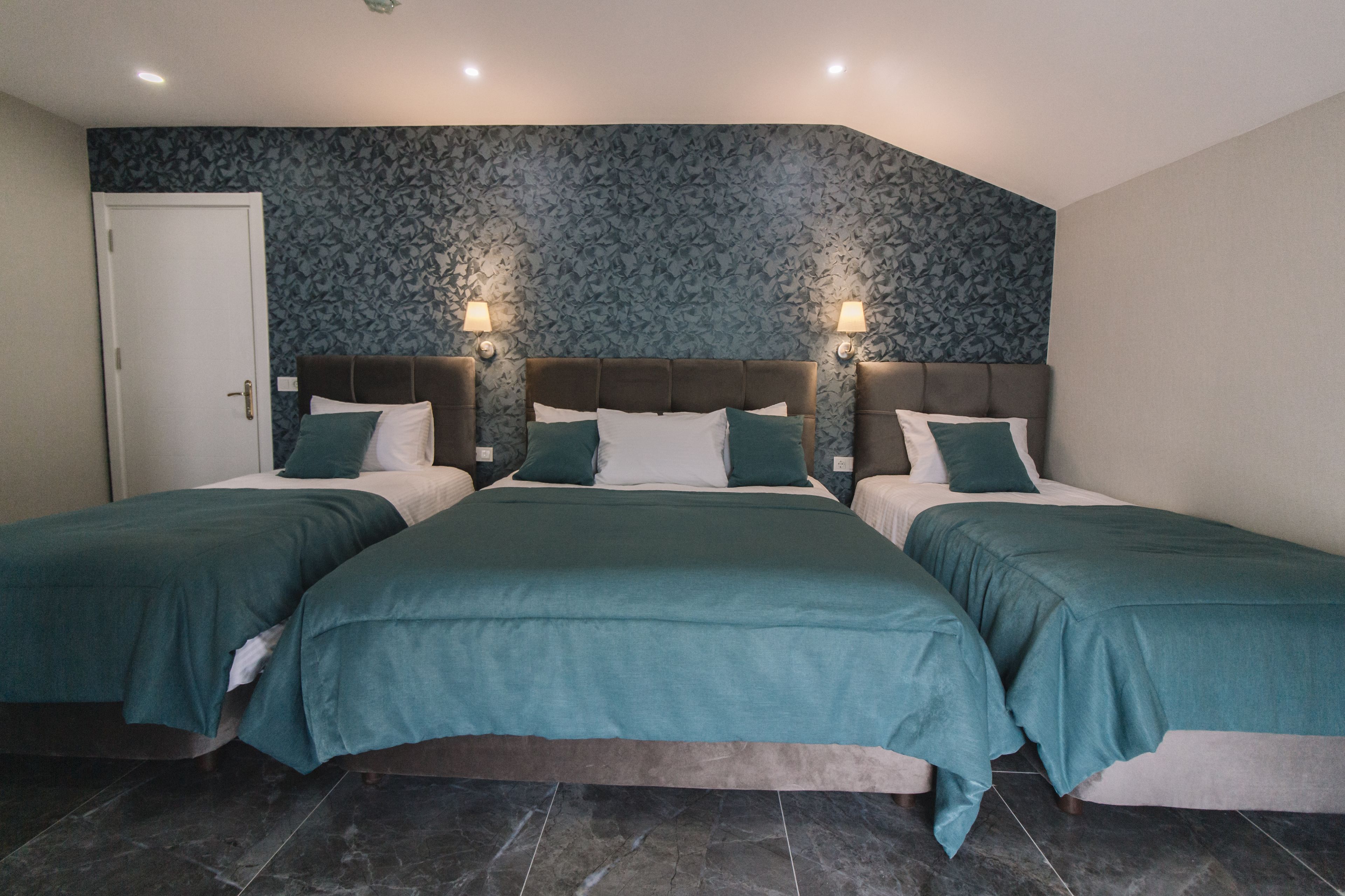 Una habitación de hotel con una cama grande, dos mesitas de noche y un papel tapiz estampado.