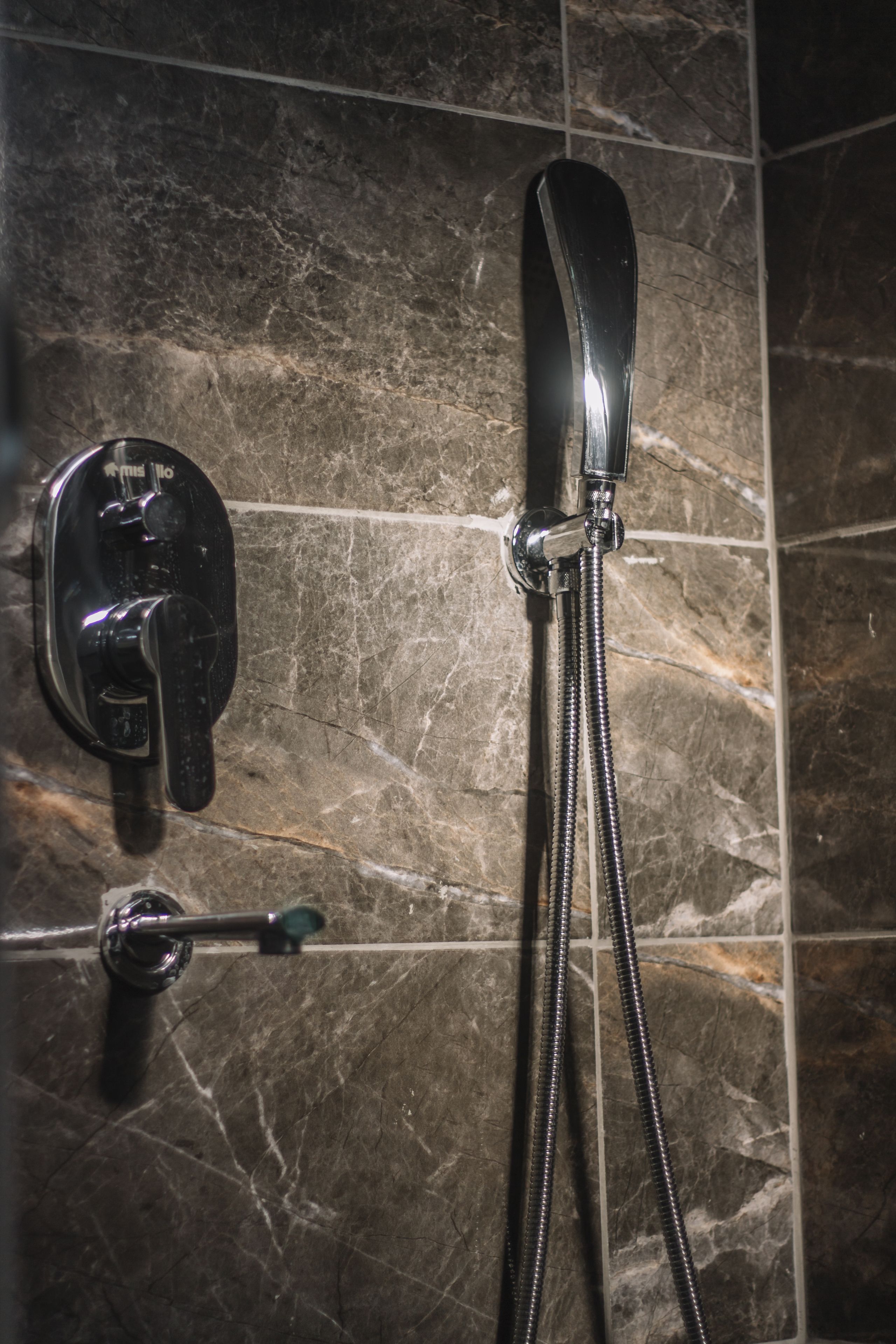 Ducha con cabezal de ducha manual y cabezal fijo, ambos instalados en una pared con azulejos.