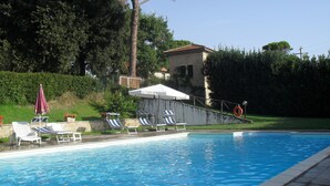 A swimming pool with lounge chairs and umbrellas, surrounded by greenery and a small building. - Residenza del Marchese (Gualdo Cattaneo)