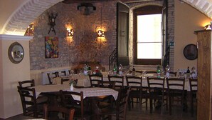 A restaurant with stone walls, wooden tables, and chairs. There are candles on the walls and a window with curtains. - Residenza del Marchese (Gualdo Cattaneo)