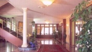Un vestíbulo amplio con piso a cuadros, una escalera y una columna grande.