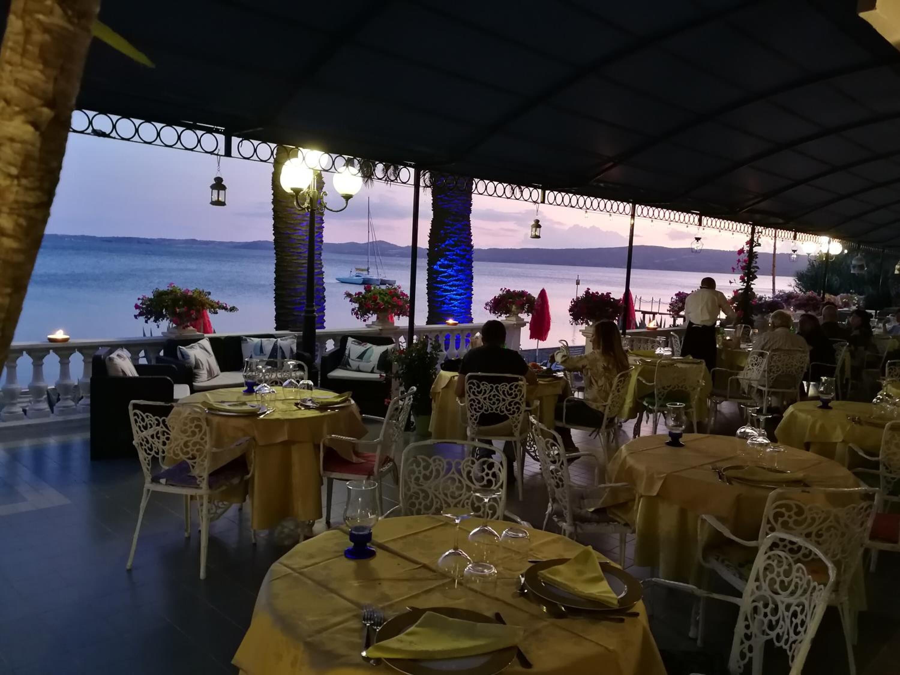 A restaurant with tables set for dining, overlooking a body of water.