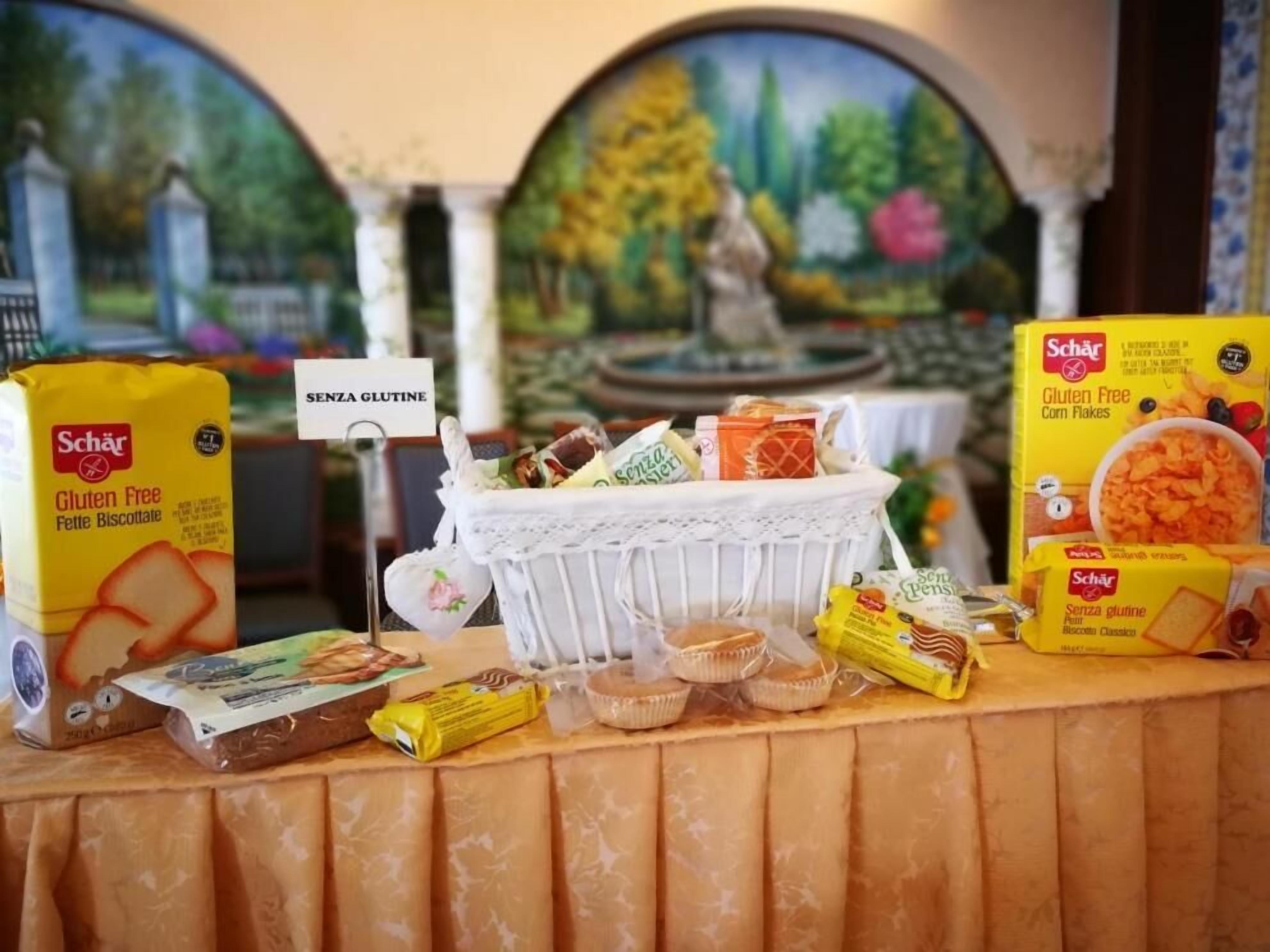 A buffet table with gluten-free options, including biscuits and corn flakes, and a sign indicating gluten-free availability.