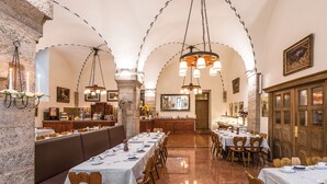 A restaurant with a long dining table, multiple seating areas, and a stone wall. - Hotel Garni Altes Brauhaus (Rothenburg ob der Tauber)