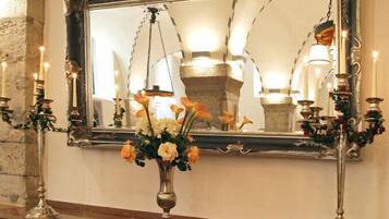 Un espejo con un marco decorativo, un jarrón con flores y candelabros en una pared.