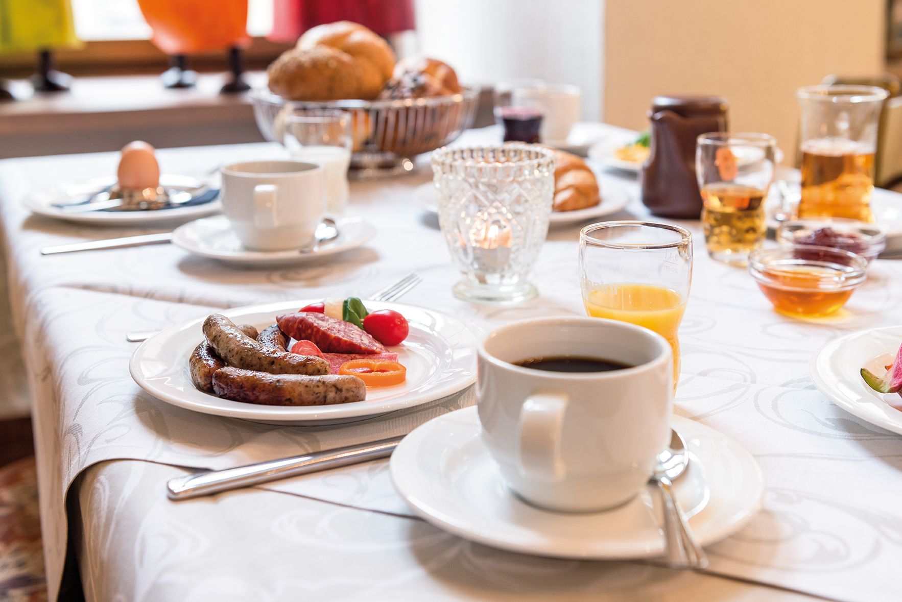 A breakfast table with plates of food, cups of coffee, and glasses of juice.