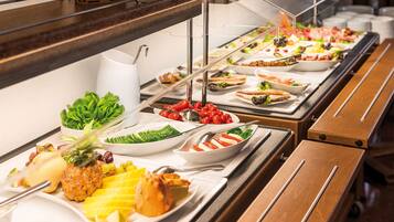 Un buffet con un'ampia scelta di cibi, tra cui frutta, insalate e carni.