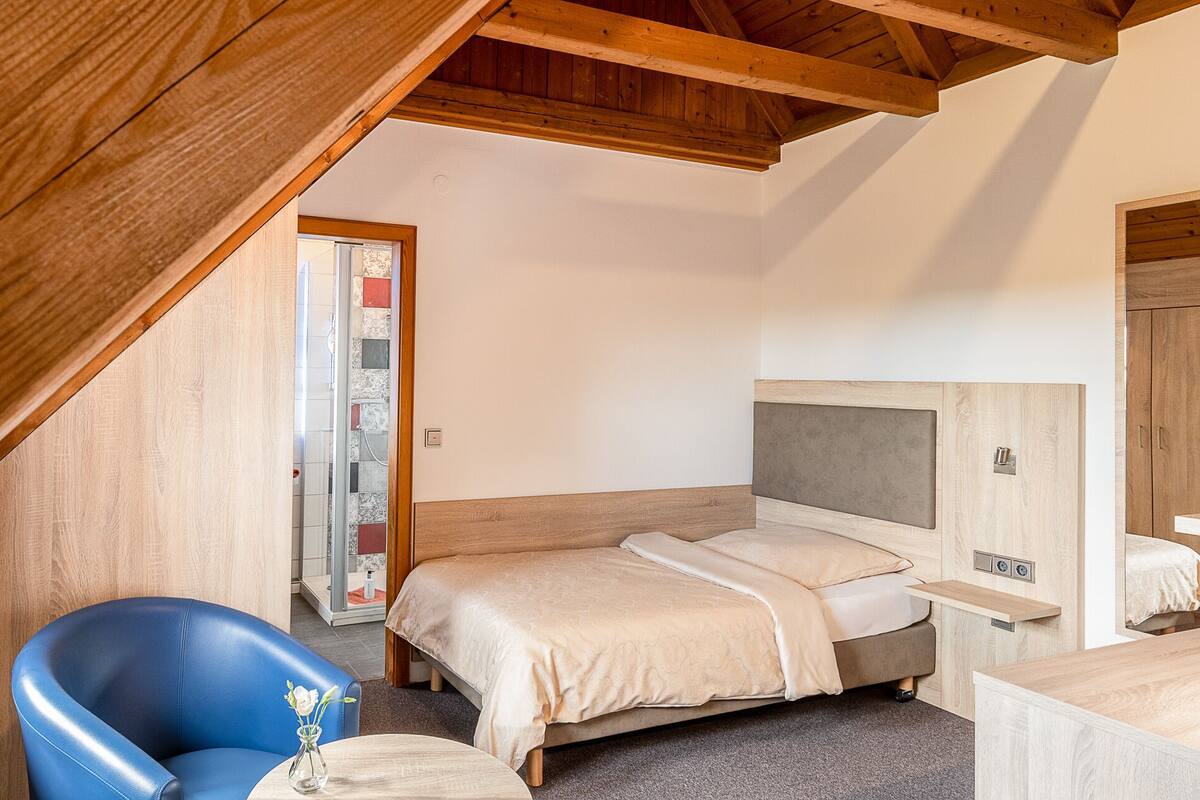 Un dormitorio con cama, una silla y techo de madera.