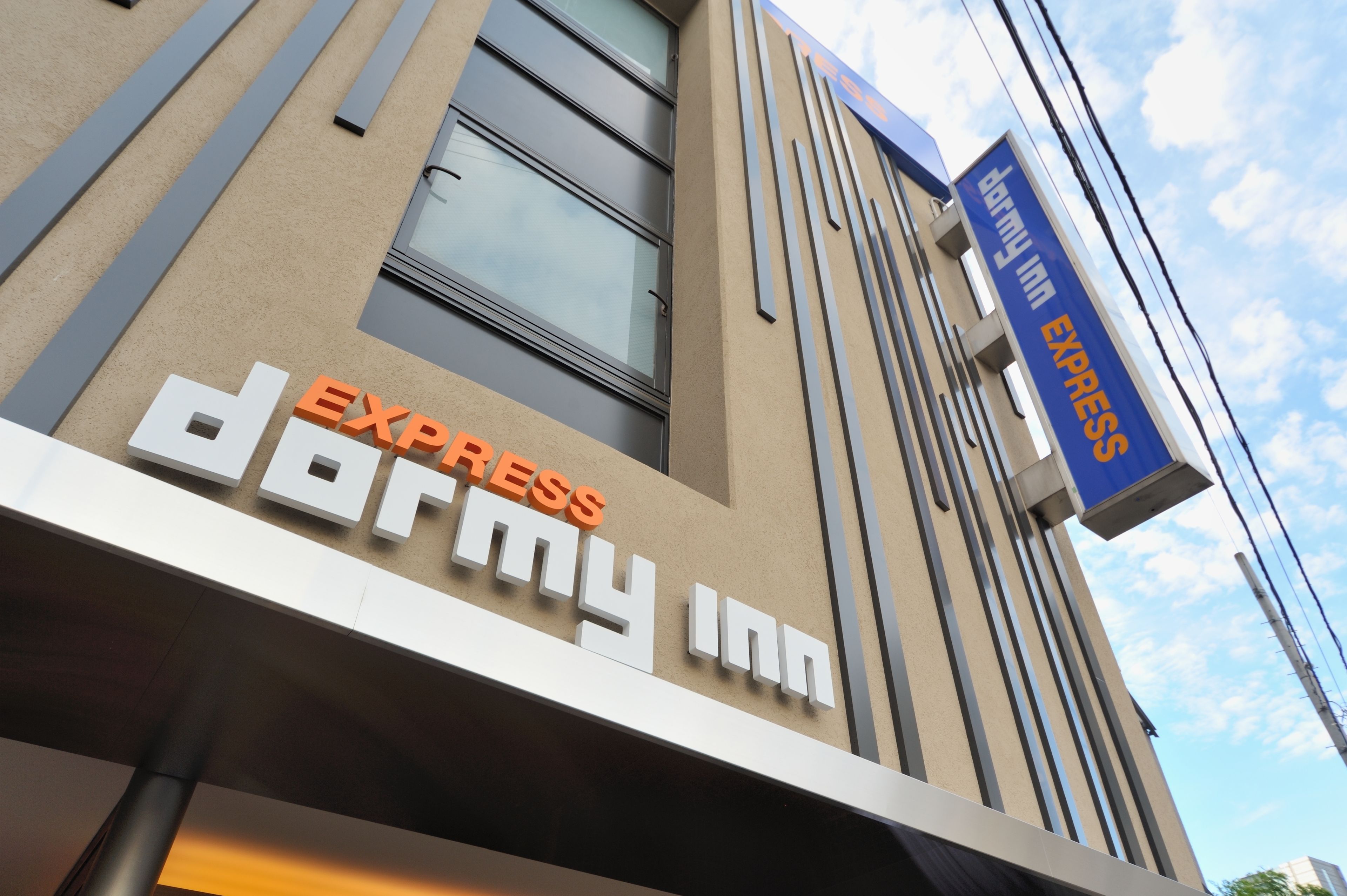 Fachada de un edificio con letreros que indican 'Express Dormy Inn' y 'Dairy Inn Express'.