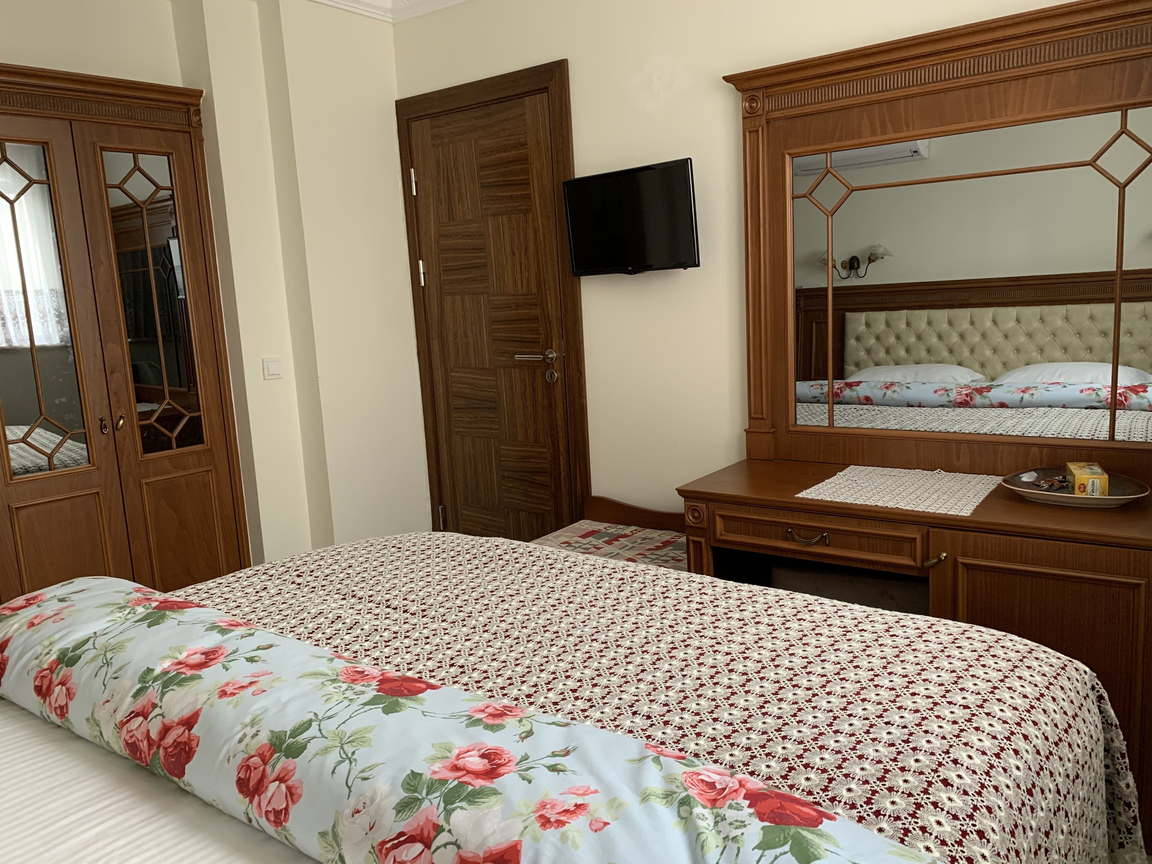 A bedroom with a bed, a dresser, a mirror, and a television.