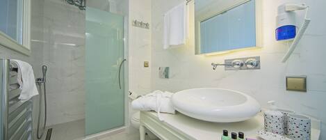 A modern bathroom with a glass-enclosed shower, a white sink, and a vanity with toiletries.