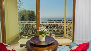 Een balkon met uitzicht op zee, een bloempot en een houten tafel.