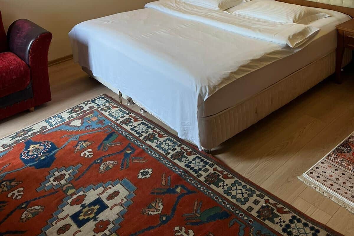 A hotel room with a large bed, a red armchair, and a patterned rug.