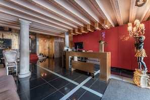 Welcome to the grand lobby, featuring a reception desk, a striking column, and a decorative statue.