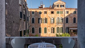 A balcony with a table set for two, overlooking a historic building with multiple windows and a balcony. - Il sogno di Giulietta e Romeo (Venice)