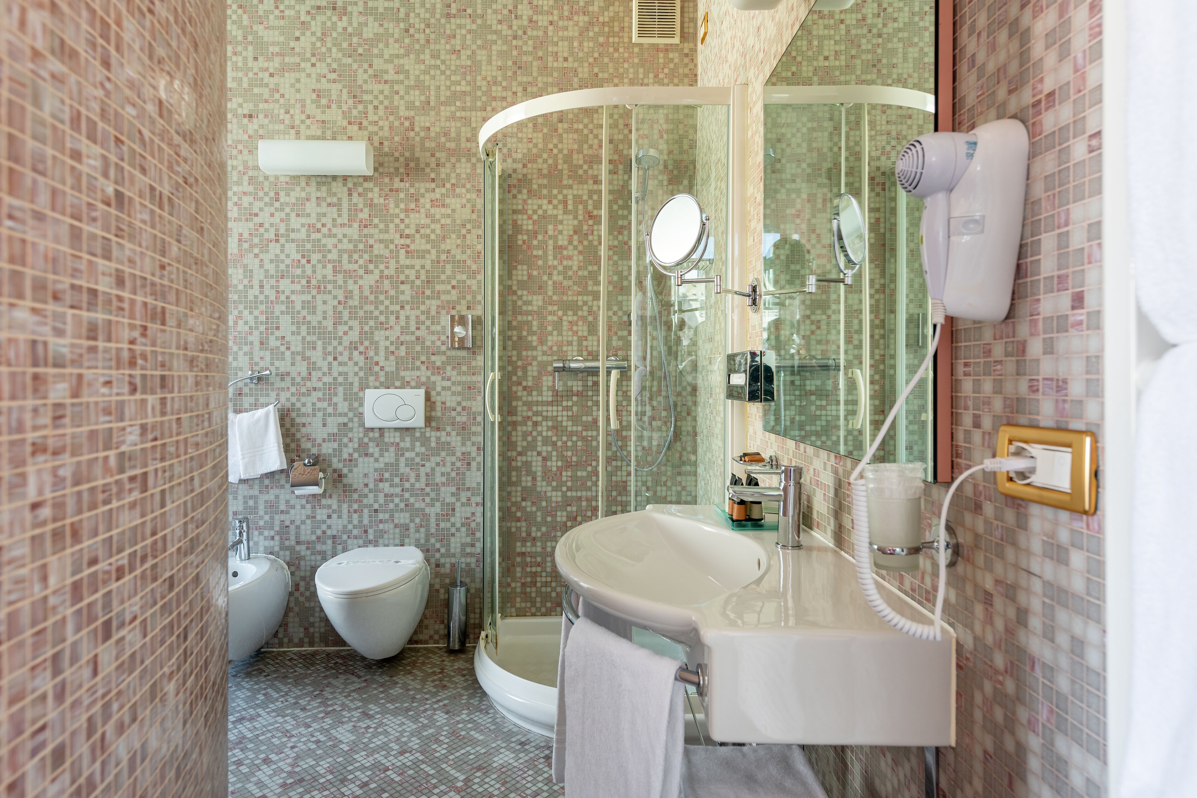 A bathroom with a glass-enclosed shower, a white sink, and a toilet.