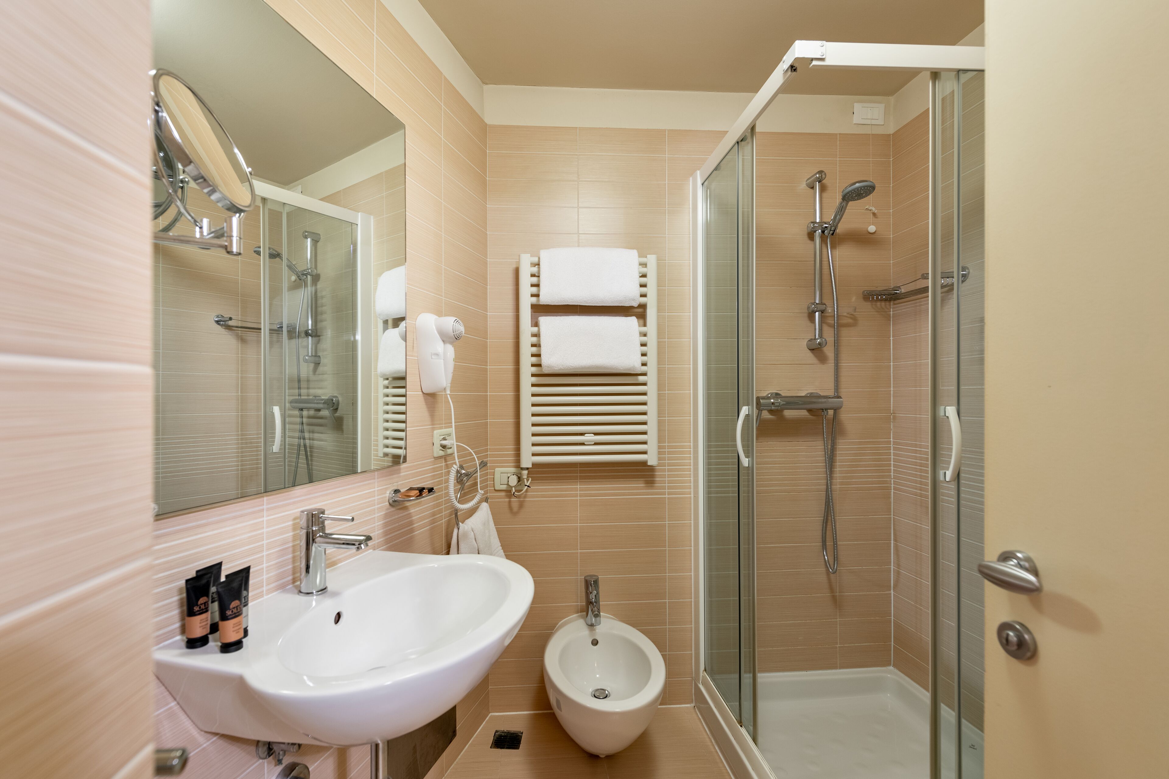 A modern bathroom with a sink, bidet, and glass-enclosed shower.