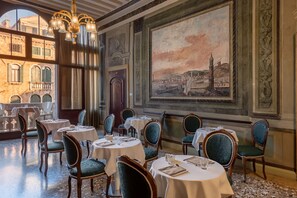 A dining area with round tables, chairs, and a large painting on the wall. - Il sogno di Giulietta e Romeo (Venice)