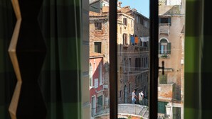 A view through a window of a narrow street with buildings, a bridge, and a canal. - Il sogno di Giulietta e Romeo (Venice)