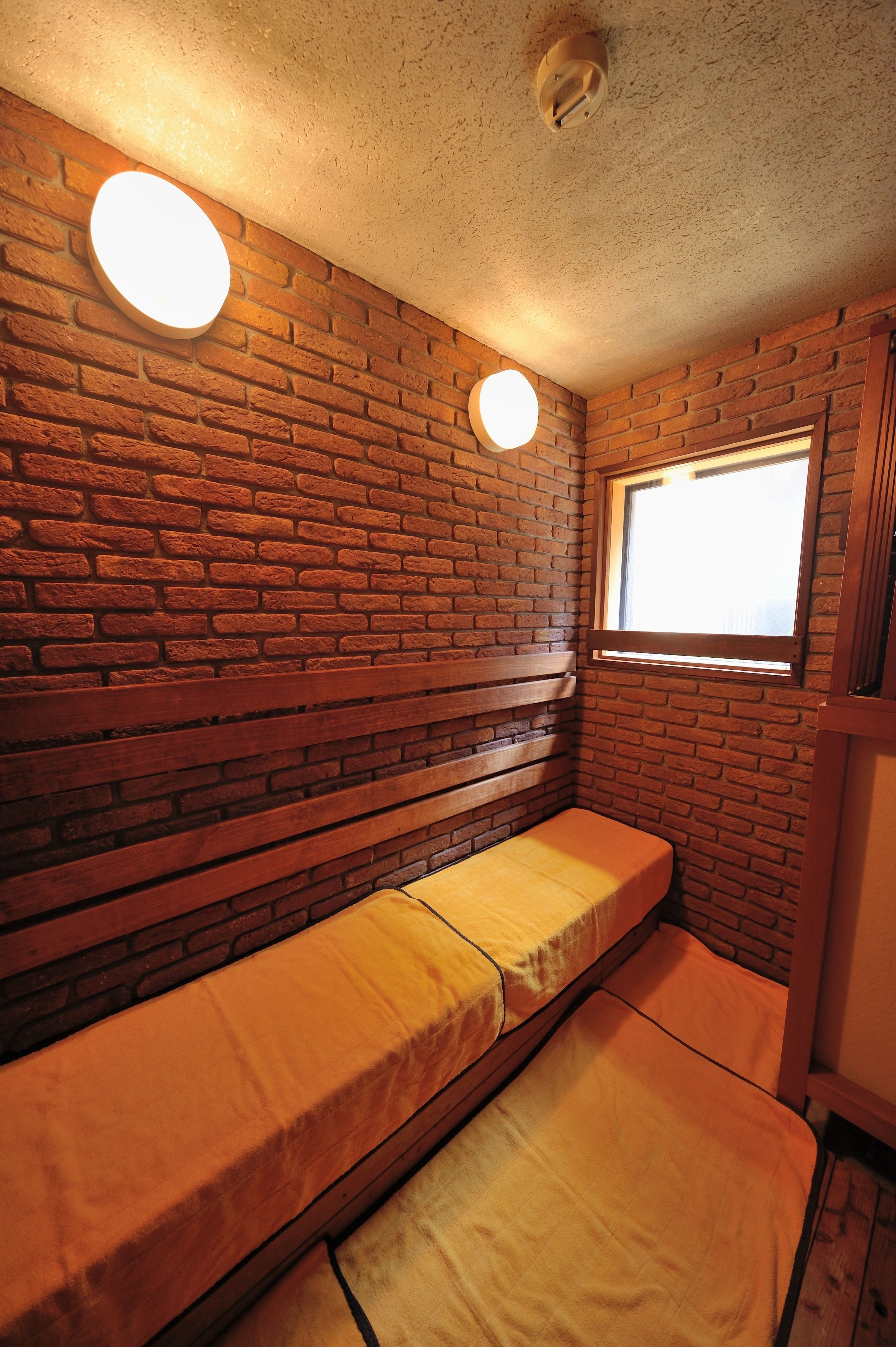 Una habitación pequeña y acogedora con pared de ladrillo, un banco y una ventana.