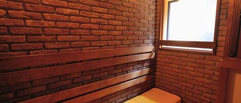 Una habitación pequeña y acogedora con pared de ladrillo, un banco y una ventana.