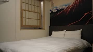 A bedroom with a bed, a window with a wooden frame, and a wall with a painting of a mountain.