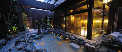 A serene indoor garden with a koi pond, stone pathway, and wooden seating area.