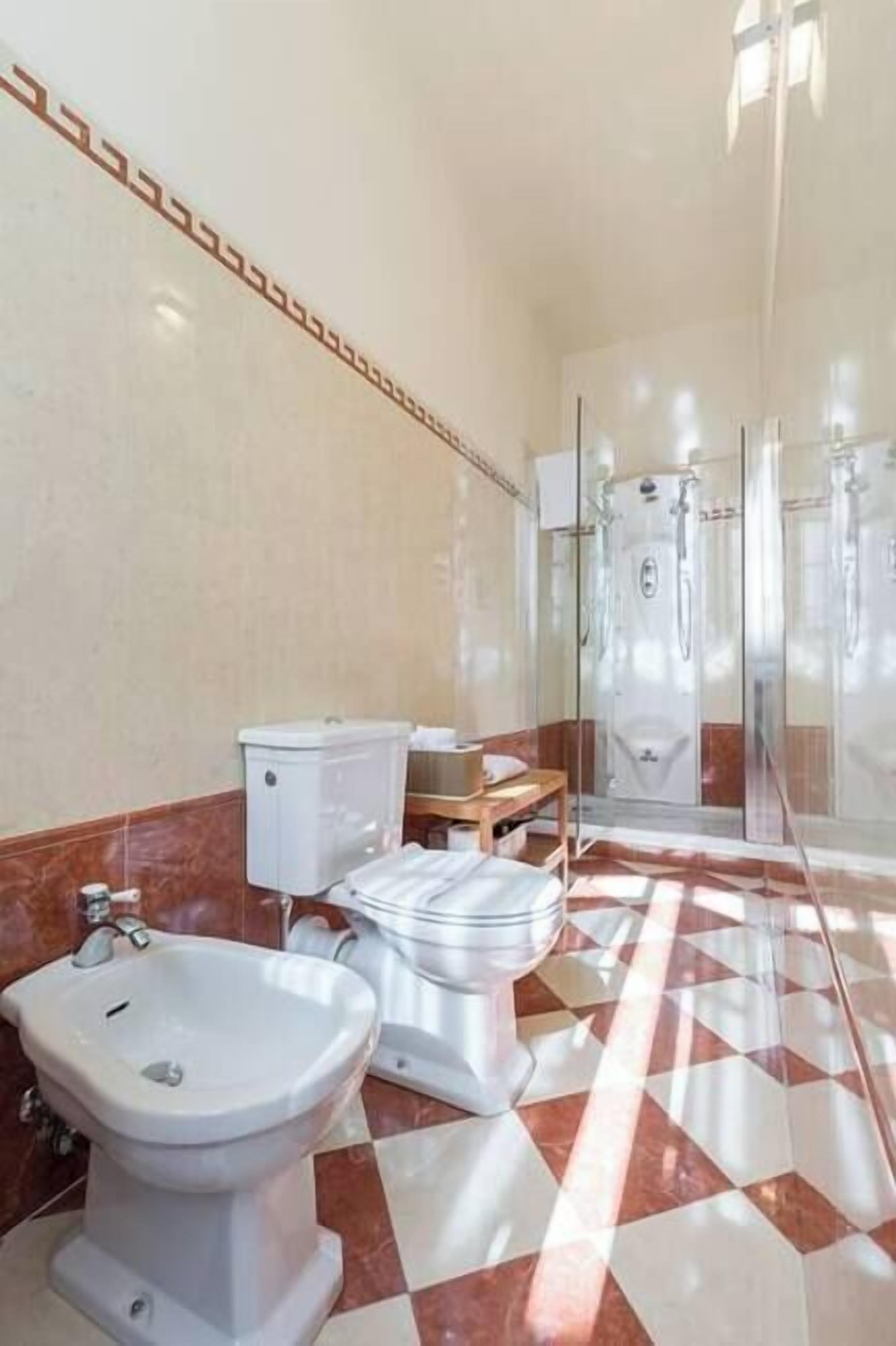 Une salle de bain équipée d’un bidet, de toilettes et d’une douche.