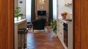 A narrow hallway leading to a dining area with a TV, a chair, and a plant. - Palazzo Alfani al David (Florence)