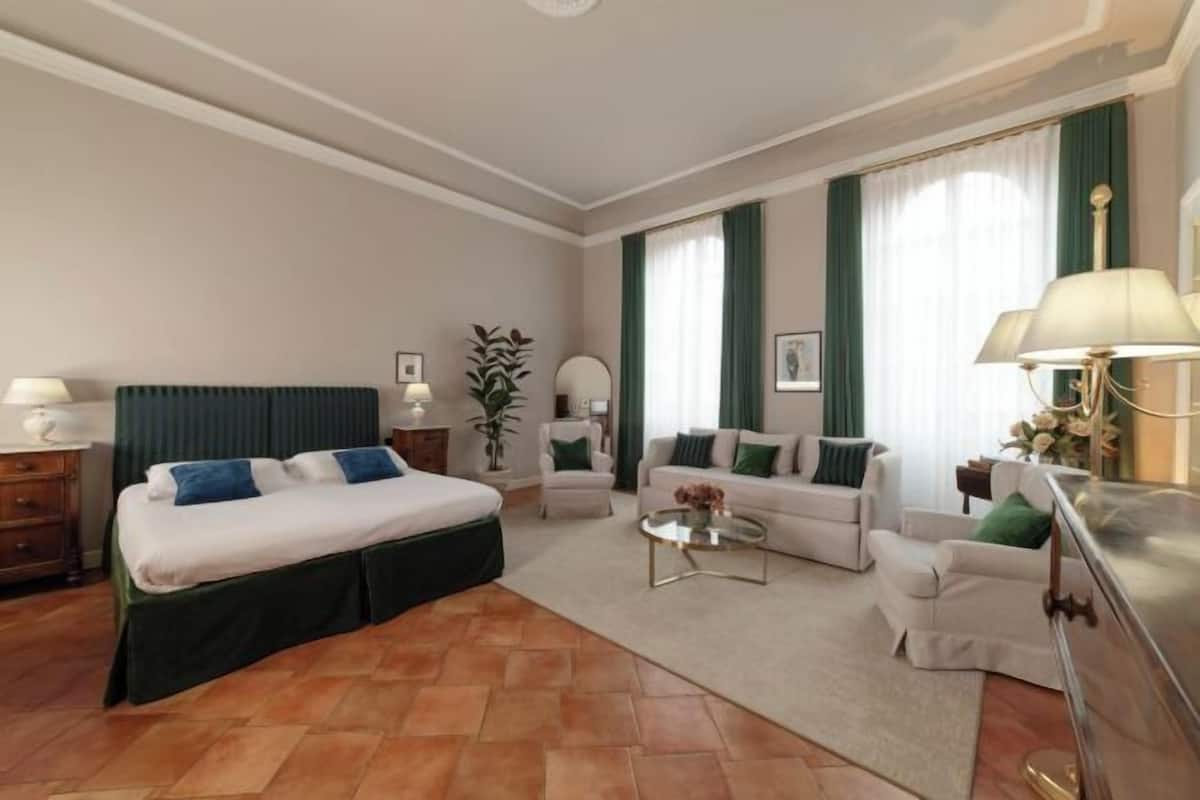 A hotel room with a bed, two sofas, a coffee table, and a desk.