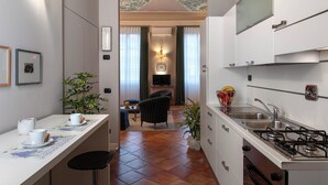 A compact kitchen with a gas stove, a sink, and a dining area with a table and chairs. - Palazzo Alfani al David (Florence)