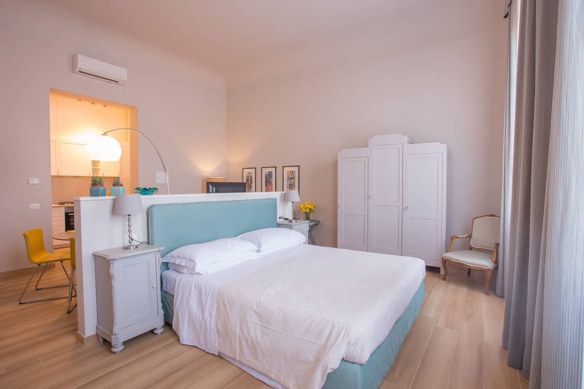 A bedroom with a bed, bedside tables, a lamp, a chair, a wardrobe, and a desk with a chair.