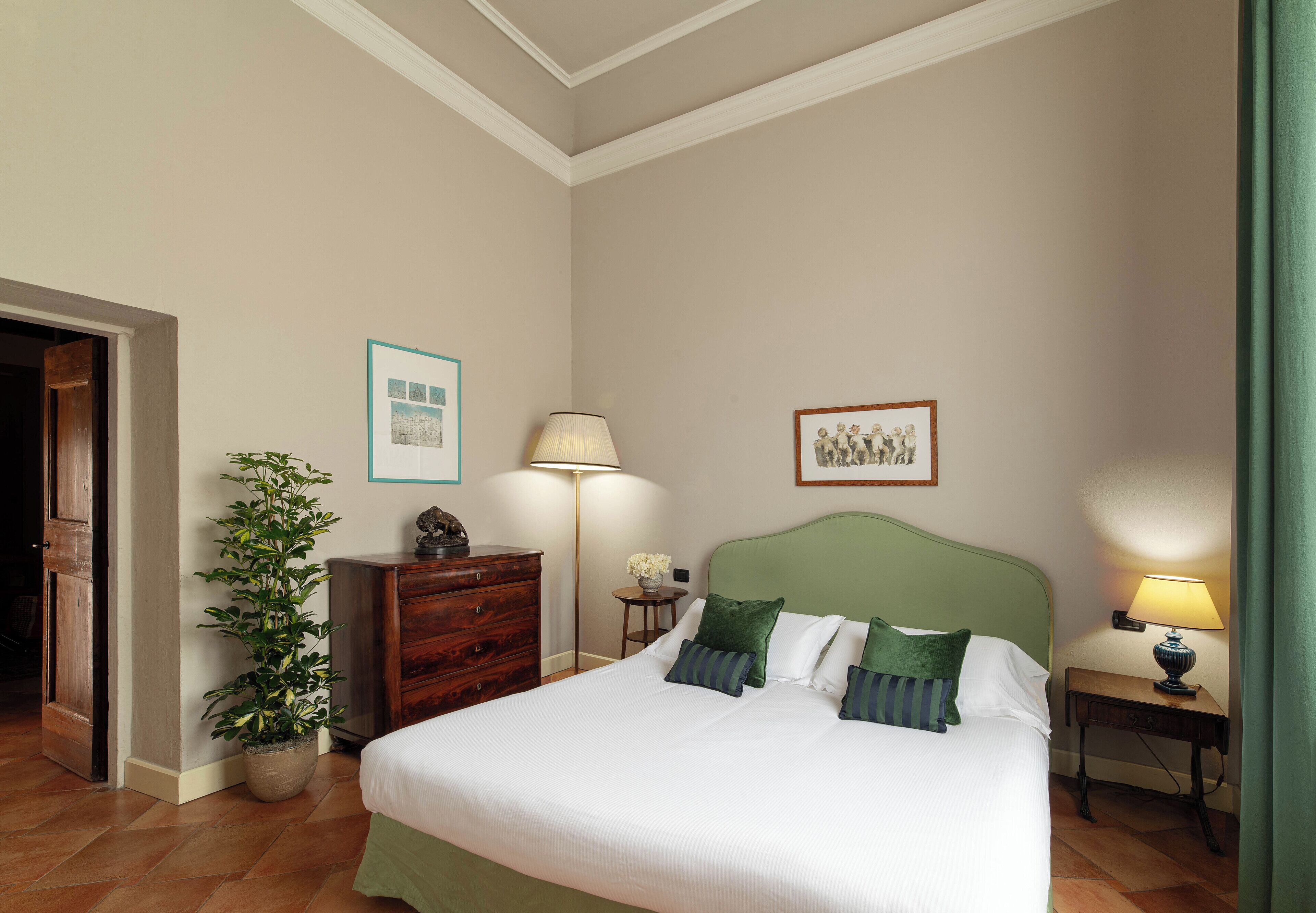 Ein ordentlich eingerichtetes Schlafzimmer mit Bett, Nachttischen, einer Lampe, einem Schminktisch und einem Blumentopf.