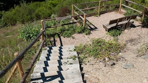 A wooden staircase leading up to a viewing platform with a bench, surrounded by greenery and overlooking a lake. - Hotel im Rheintal (Kamp-Bornhofen)