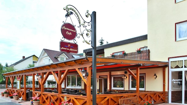 A restaurant with outdoor seating, a wooden pergola, and potted flowers. - Hotel im Rheintal (Kamp-Bornhofen)