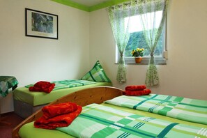 A room with two beds, a window with curtains, a framed picture on the wall, and a small table with a green tablecloth. - Hotel im Rheintal (Kamp-Bornhofen)