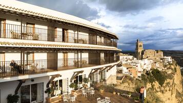 Um hotel com terraço, mobiliado com área de estar ao ar livre, vista para uma cidade histórica e uma torre de igreja imponente ao fundo.