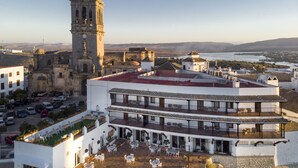 A hotel with a rooftop terrace, a bell tower, and a view of the surrounding landscape.
