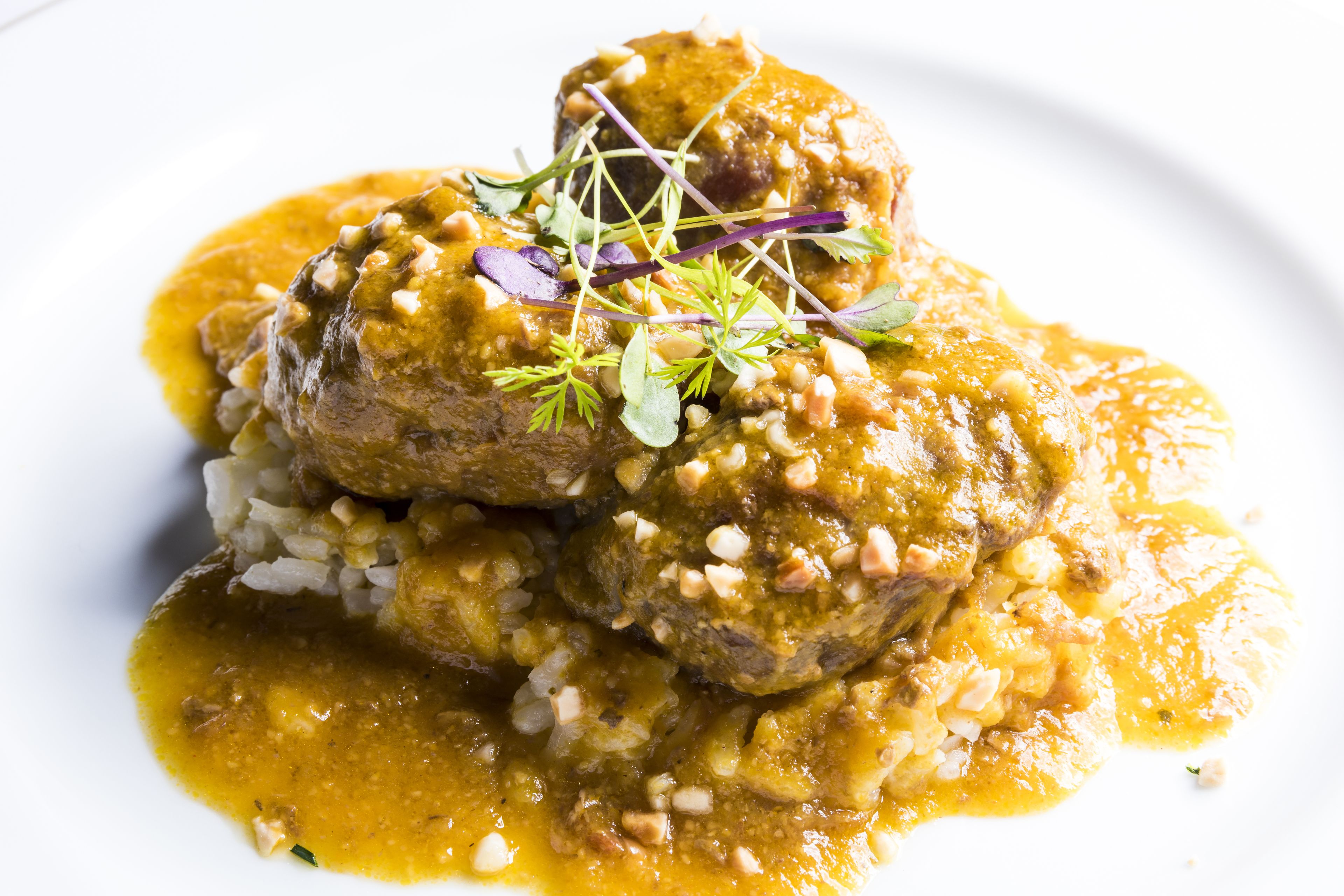 Un plat composé de boulettes de viande et d’une sauce, garni d’herbes et de noix.