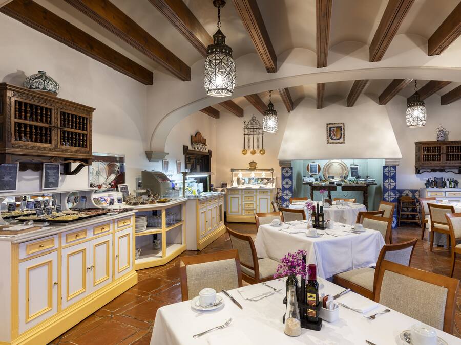 Un restaurante con vigas de madera, paredes blancas y mesas dispuestas para comer.