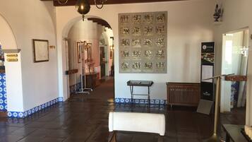 Un vestíbulo amplio con candelabro, suelo de baldosas y una pared decorada con obras enmarcadas.
