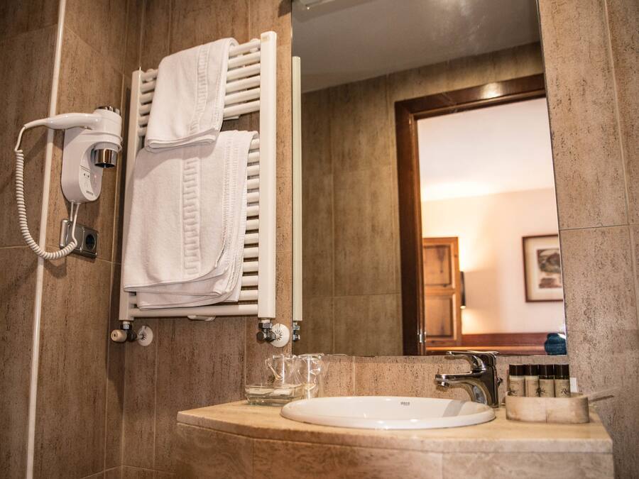 Un baño con lavamanos de mármol, toallero, secador de pelo y artículos de aseo en la encimera.