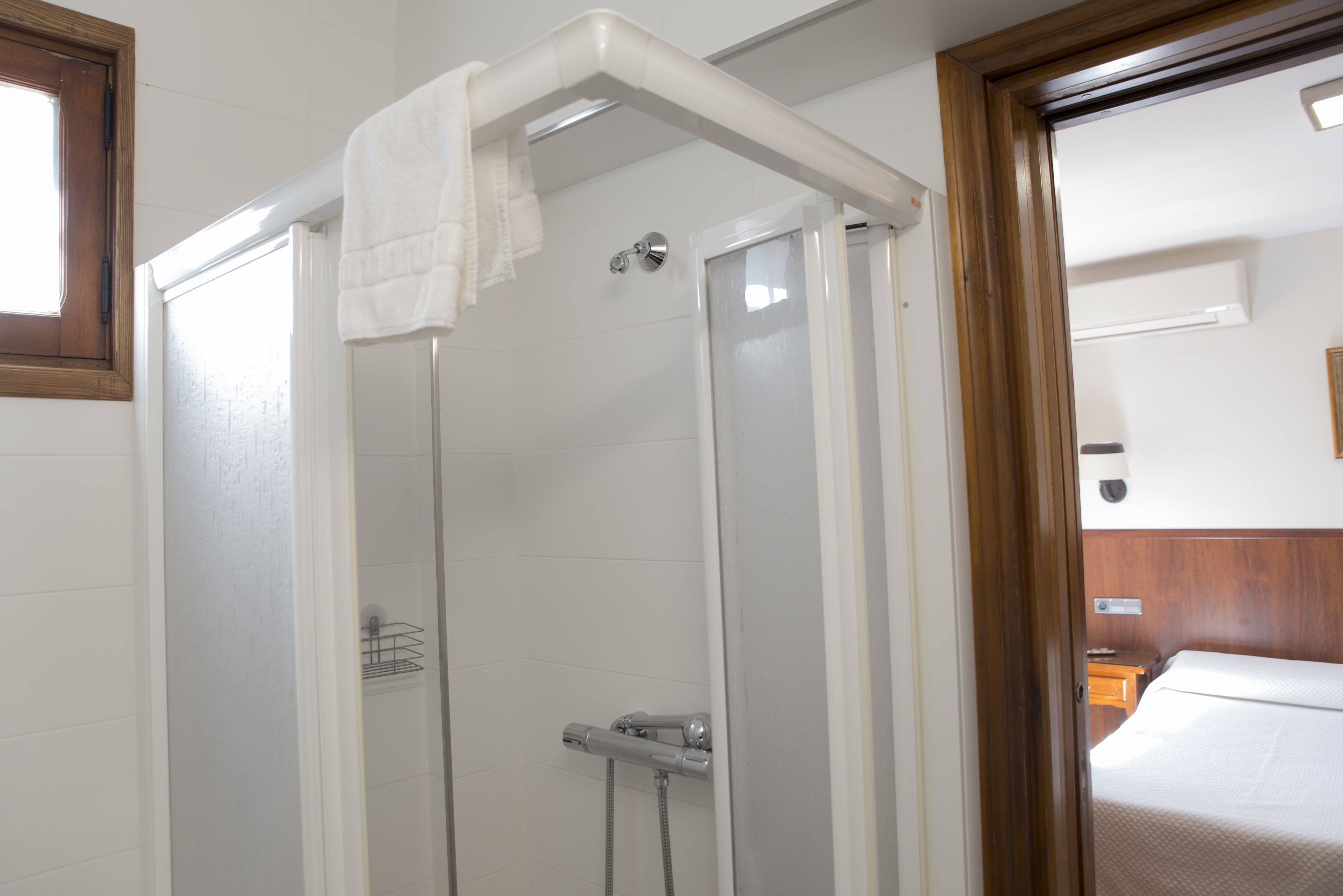 A shower enclosure with a towel hanging on the door, a showerhead, and a control panel.