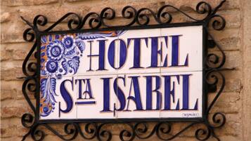 Een hotelsbord met de naam 'HOTEL STA ISABEL' in grote, vetgedrukte letters, omringd door decoratieve patronen.