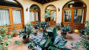 Un pati amb molts gots de plantes, arcs de fusta i paviment de rajoles.