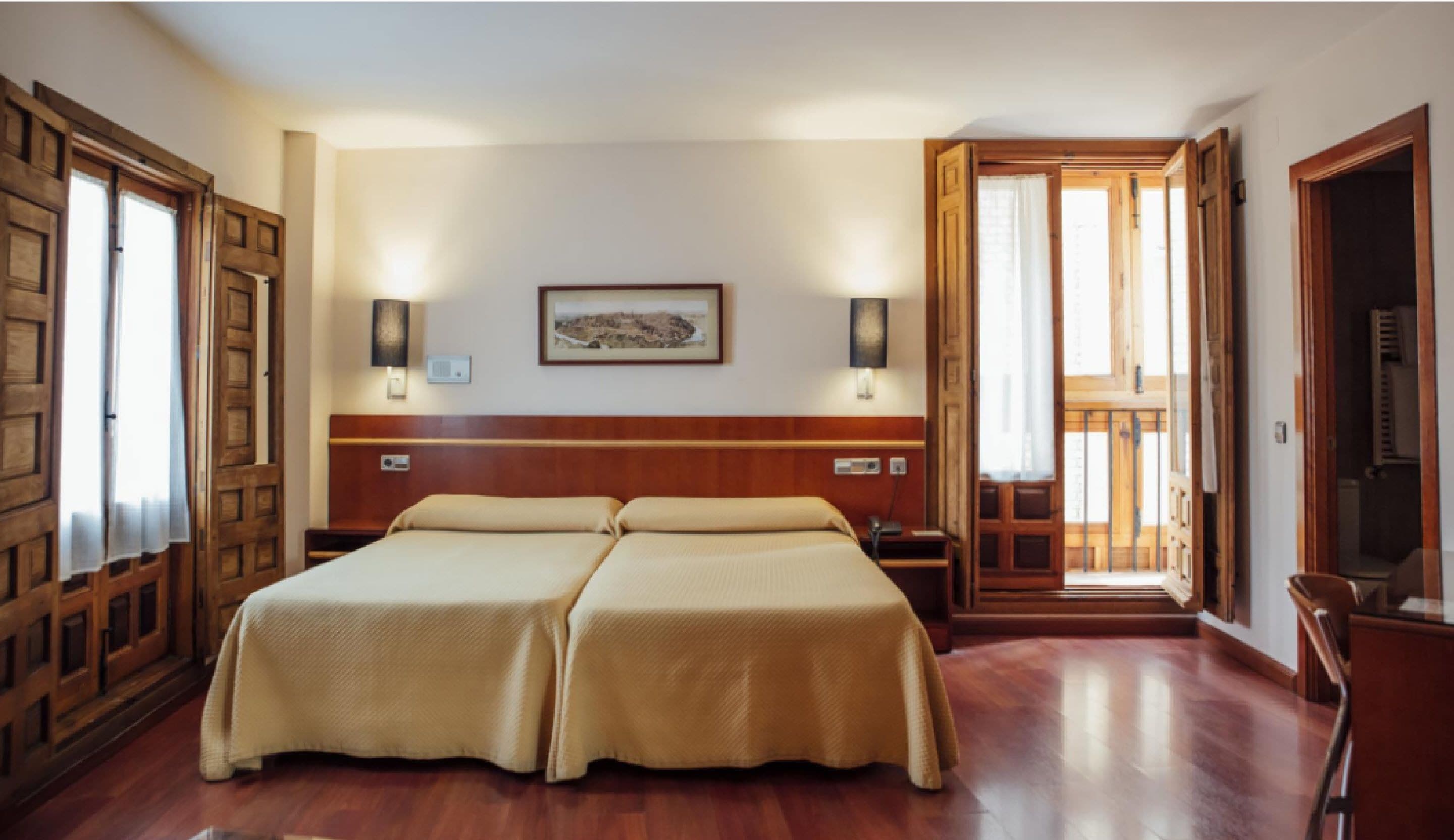 A double bed with a wooden headboard, two bedside tables, wall-mounted lamps, and a framed picture on the wall.
