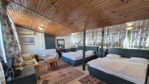 Ein Zimmer mit Holzboden, zwei Betten mit Kopfteilen, einem Schreibtisch, einem Stuhl und einem Fernseher.