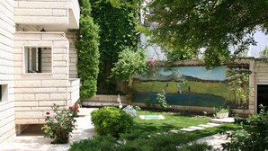 Ein Innenhof mit einem Steinhaus, einem Wandgemälde und einem kleinen Teich.
